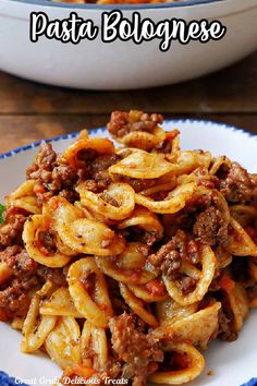 pasta bolognzoe with meat and sauce in a white bowl on a blue and white plate