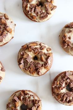 chocolate donuts with white frosting and chopped nuts on top, lined up in rows