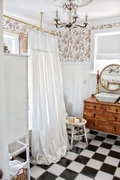 a bathroom with black and white checkered flooring, shower curtain, sink and mirror