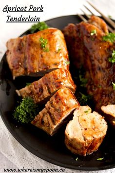 some meat is on a black plate and garnished with parsley