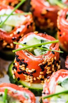 many different types of food are arranged on a plate with sesame seeds and cucumbers