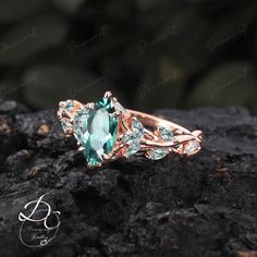 a ring with an aqua green stone surrounded by white diamonds on top of a rock