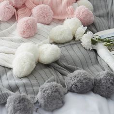 several pom poms are laying on a bed next to a magazine and flowers