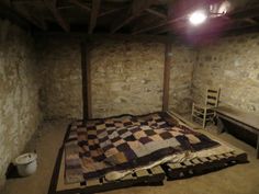 an empty room with a bed, chair and table in the corner next to it