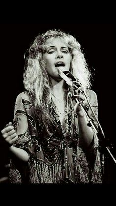 a black and white photo of a woman singing into a microphone