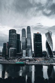 an aerial view of a city with tall buildings and water in the foreground on a cloudy day