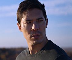 a close up of a person wearing a black shirt and looking off into the distance