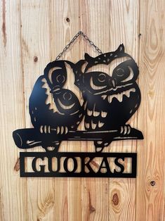 two metal owls sitting on top of a sign