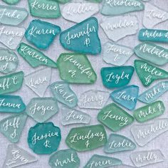 sea glass hearts with names on them sitting on a cloth covered table next to each other