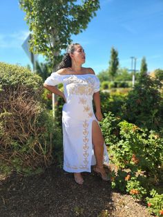 a woman in a white dress standing next to bushes