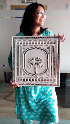 a woman is holding up a metal plaque