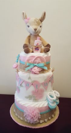 a three tiered cake with a stuffed animal sitting on it's top layer