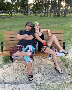 two people sitting on a bench in the park