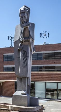 a large statue in front of a brick building