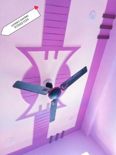 a ceiling fan in the middle of a room with pink walls and purple trim around it