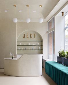 a white counter sitting in the middle of a room next to a blue bench and windows