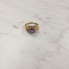 14kt Yellow Gold Lady's Diamond and Tanzanite Ring consisting of a 7mm x 5mm genuine Oval Tanzanite gemstone approx. 1.00ct total weight and 12 full cut round brilliant diamonds .25ct total weight SI clarity, H color all prong set surrounding the Tanzanite in a halo effect. The sparkle and glitter that comes from this ring will pack a punch for the wearer. The tapered shank will be comfortable and is a size 7. This Item would Retail for $875.00 Classic Tanzanite Birthstone Ring, Gold Tanzanite Birthstone Ring For Anniversary, Gold Tanzanite Gemstone Rings, Formal Tanzanite Birthstone Ring, Classic Tanzanite Gold Ring, Classic Gold Tanzanite Ring, Oval Tanzanite Gemstones In Yellow Gold, Gold Tanzanite Rings With Accent Stones, Gold Tanzanite Birthstone Ring For Formal Events