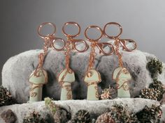 four pieces of jewelry sitting on top of a pile of snow covered rocks and pine cones