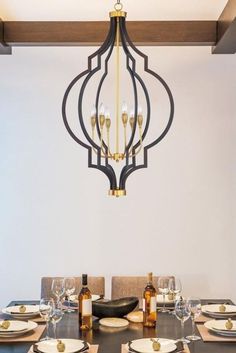 a chandelier hanging from the ceiling over a dining room table with place settings