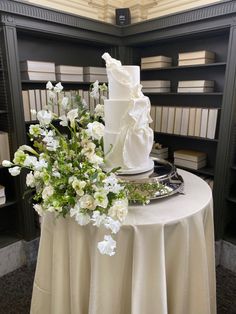 a white wedding cake sitting on top of a table next to a bouquet of flowers