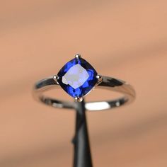 an engagement ring with a blue sapphire stone in it's setting on a black stand