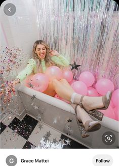 a woman sitting in a bathtub filled with balloons and confetti