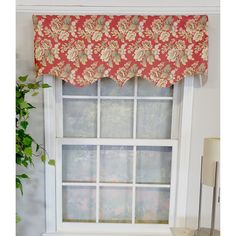 a window with a red flowered valance hanging from it's side