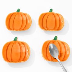 four orange pumpkins with one spoon in the middle