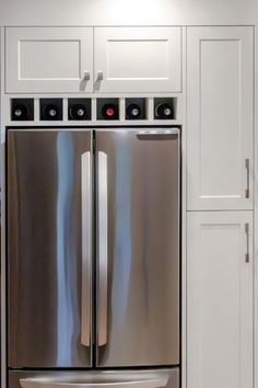 a silver refrigerator freezer sitting inside of a kitchen next to white cupboards and drawers