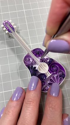 a woman with purple nail polish on her nails is cutting out an ornament