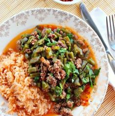 a white plate topped with rice and meat next to a bowl of sauce on top of a table