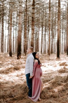 a pregnant couple standing in the woods together