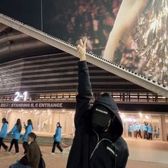 a group of people standing in front of a building at night with their hands up