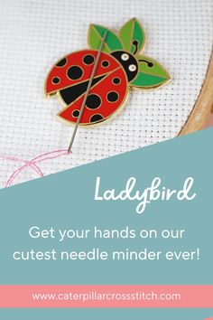 a ladybird pin sitting on top of a piece of cloth next to a needle