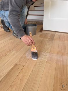 a man kneeling down on the floor with a brush