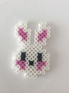 a pink and white beaded rabbit brooch on a white surface with circles around it