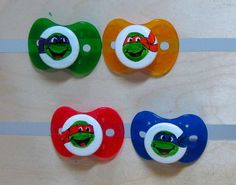 four different colored pacifiers with the same character on them