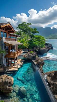 an outdoor swimming pool next to the ocean with a house on it's side