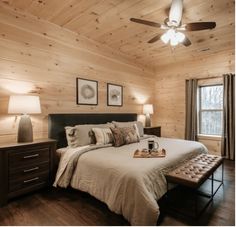 a bedroom with wood walls and ceiling fan