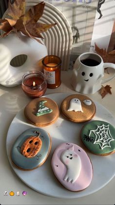 decorated cookies sitting on top of a white plate next to a cup and candle holder