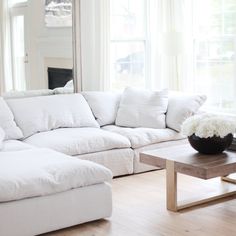 a large white couch sitting in a living room next to a table with flowers on it