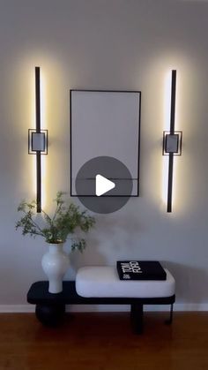 a living room with some lights on the wall and a bench in front of it