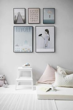 a white bedroom with pictures on the wall and a step stool in front of it