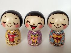 three small figurines with faces painted on them sitting next to each other in front of a white background