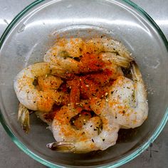 a glass bowl filled with shrimp and spices