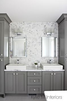 a bathroom with two sinks, mirrors and cabinets in grey color scheme on the wall