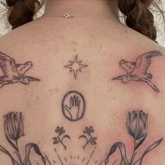 the back of a woman's shoulder with flowers and birds