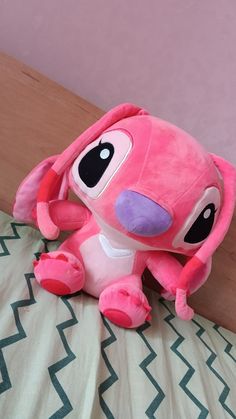 a pink stuffed animal sitting on top of a bed