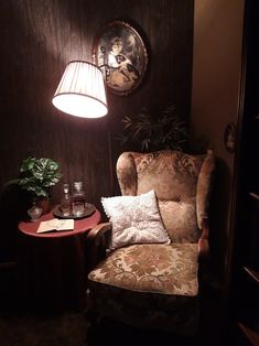 a chair and table in a room with a lamp on the wall above it,