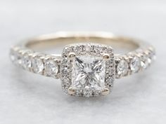 an engagement ring with a princess cut diamond surrounded by pave diamonds